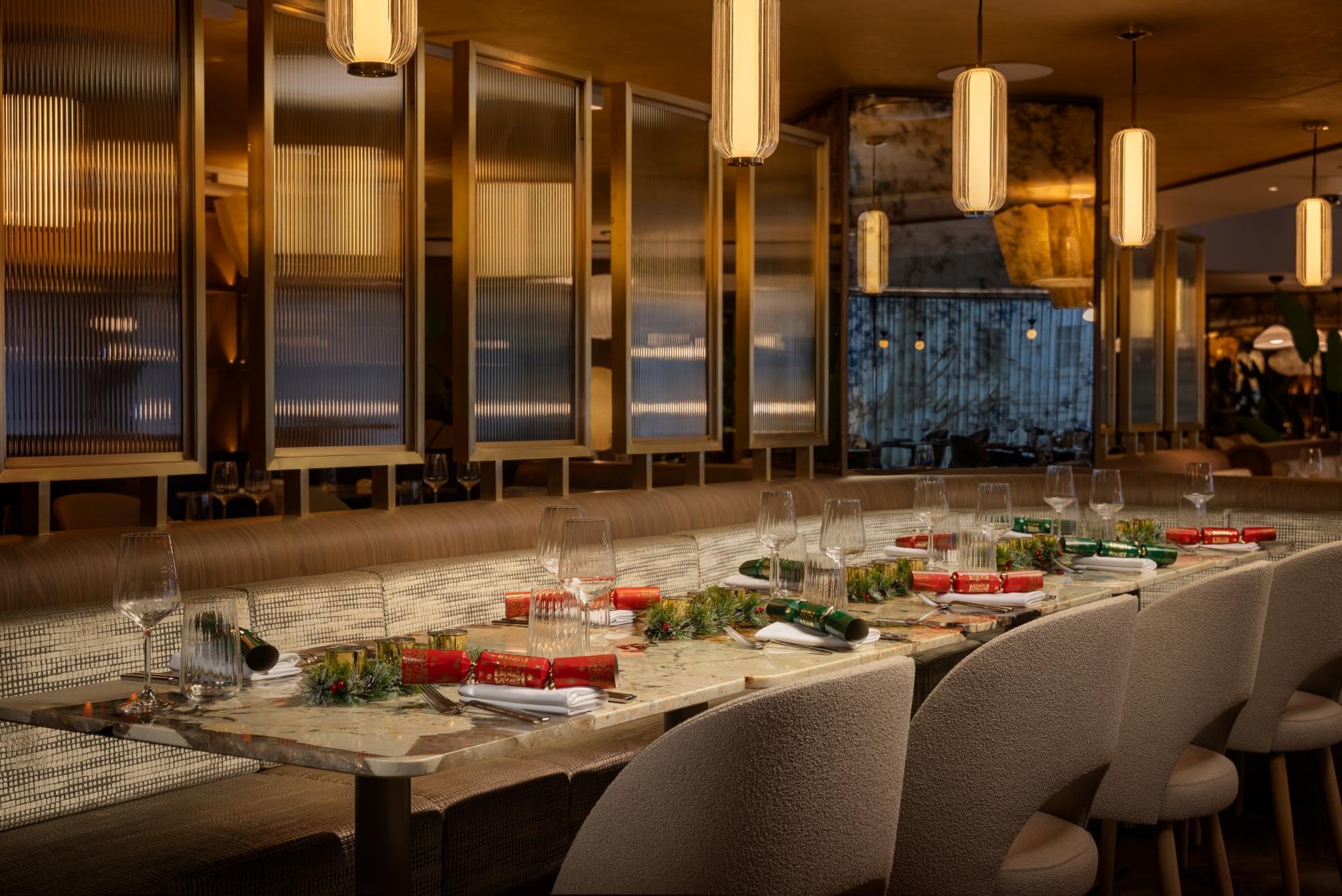 A restaurant with marble tables set with glassware, festive decorations, and pendant lighting at Barnaby's Kitchen & Lounge