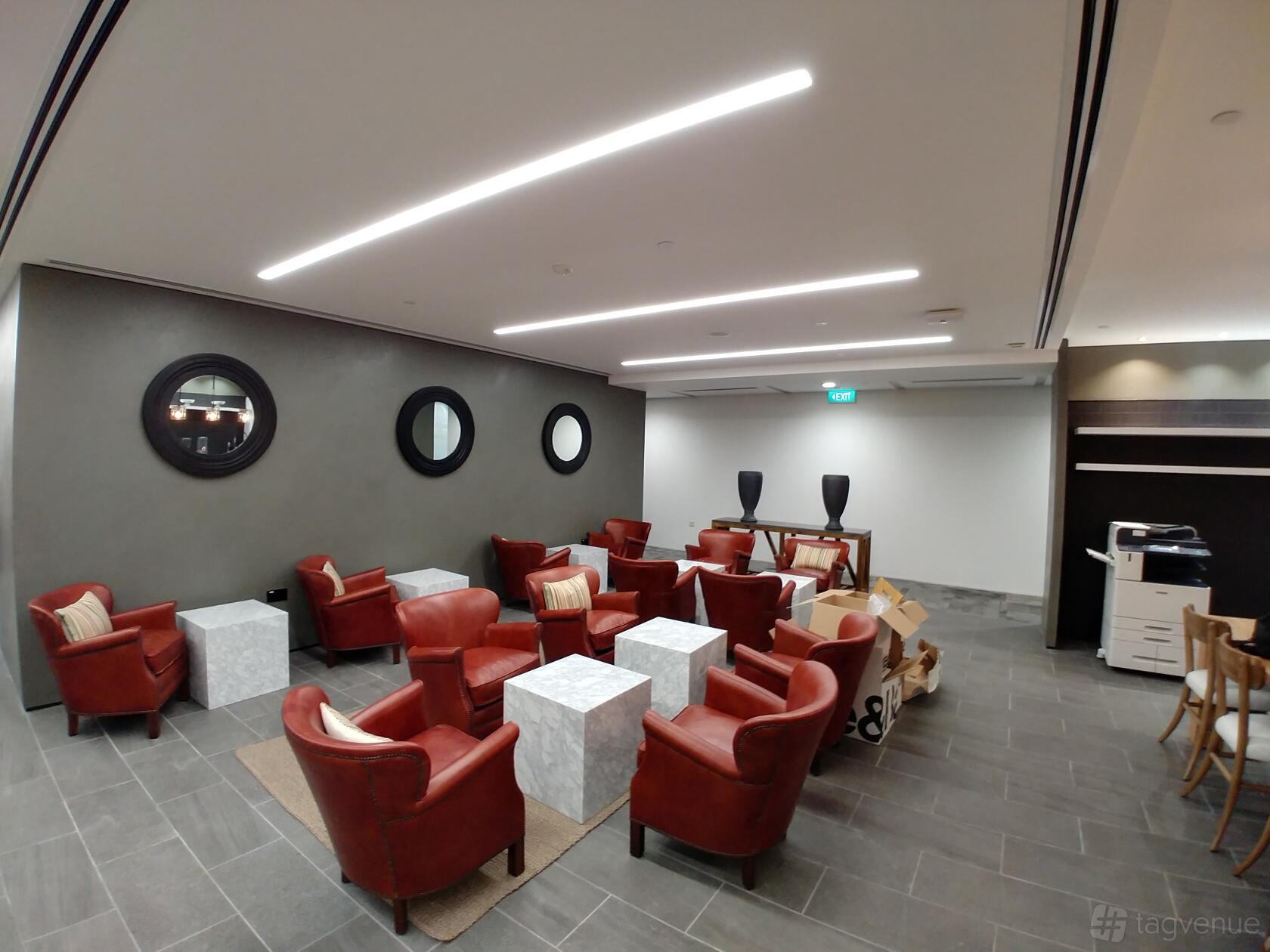 A meeting centre lounge with red leather armchairs, white square tables, and circular mirrors at The Gateway West.