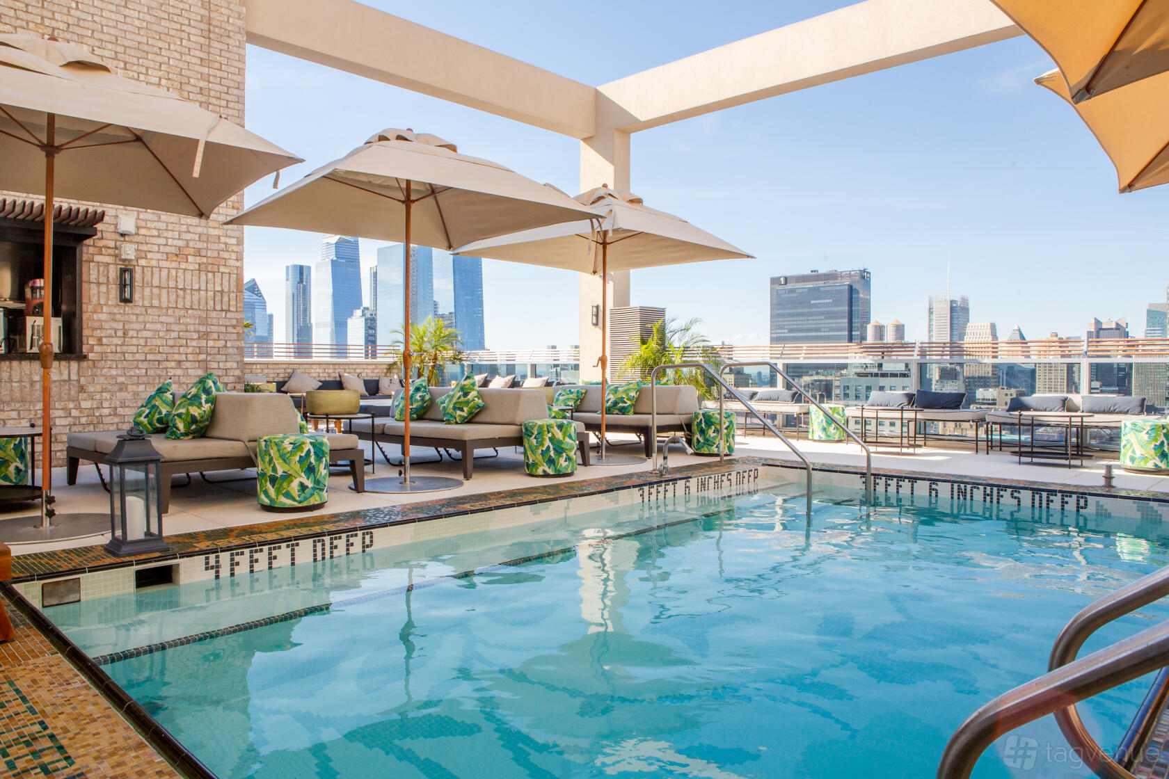 A rooftop nightclub with a pool, lounge chairs, large umbrellas, and skyline views at Somewhere Nowhere.