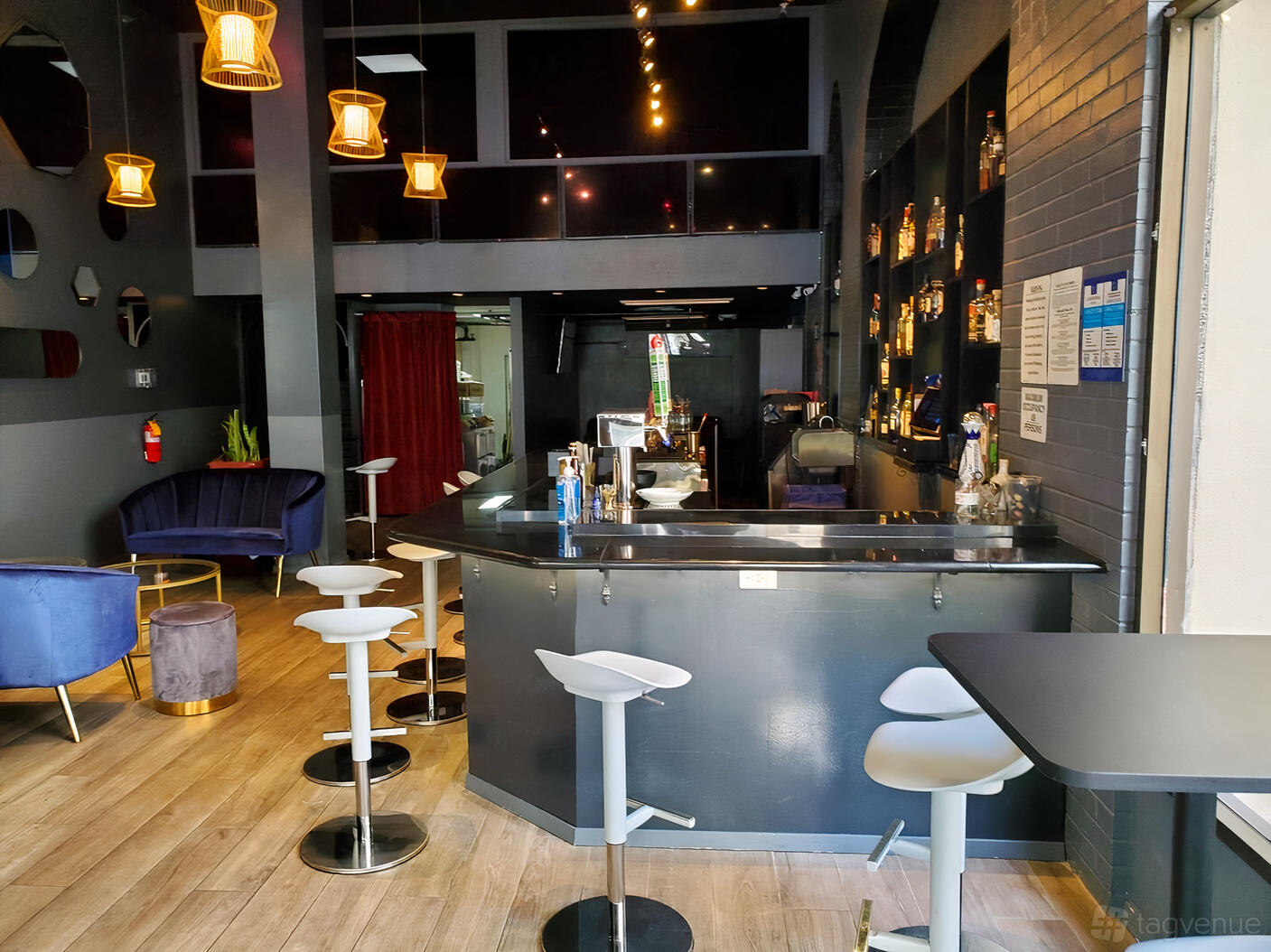 An event space with a long black bar, modern stools, wood flooring, and pendant lights at Sool Bar and Lounge.