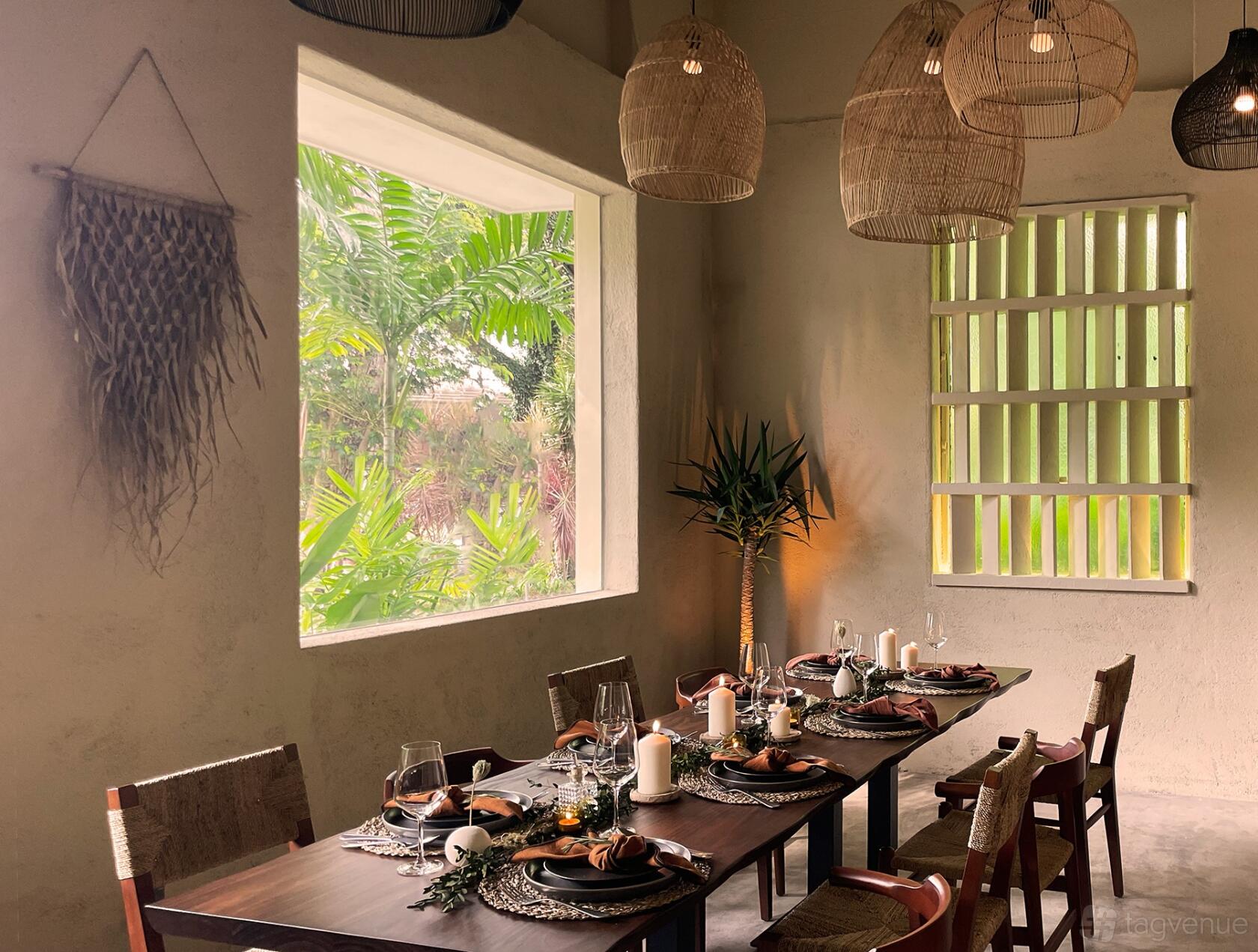 A dining room with woven pendant lights, large windows, and a set table with candles at MOXIE The Hideaway.