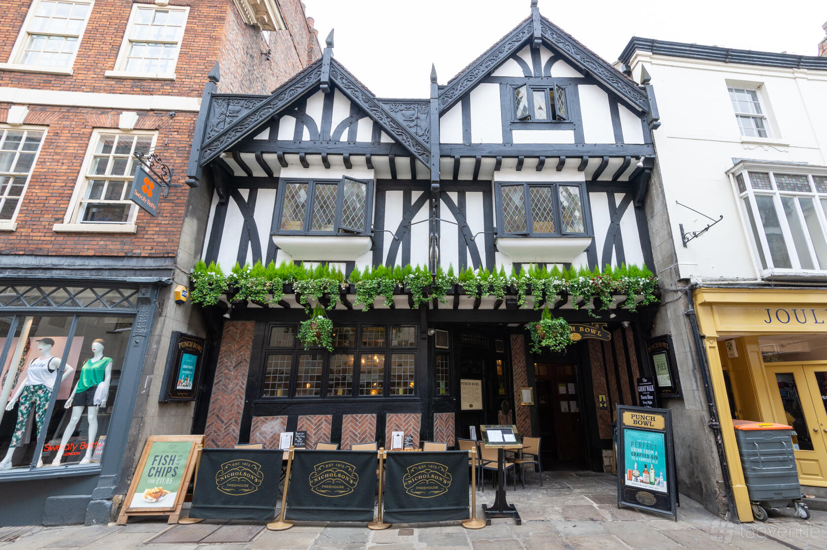 A Tudor-style pub with timber framing, leaded windows, and hanging greenery at The Pump House.