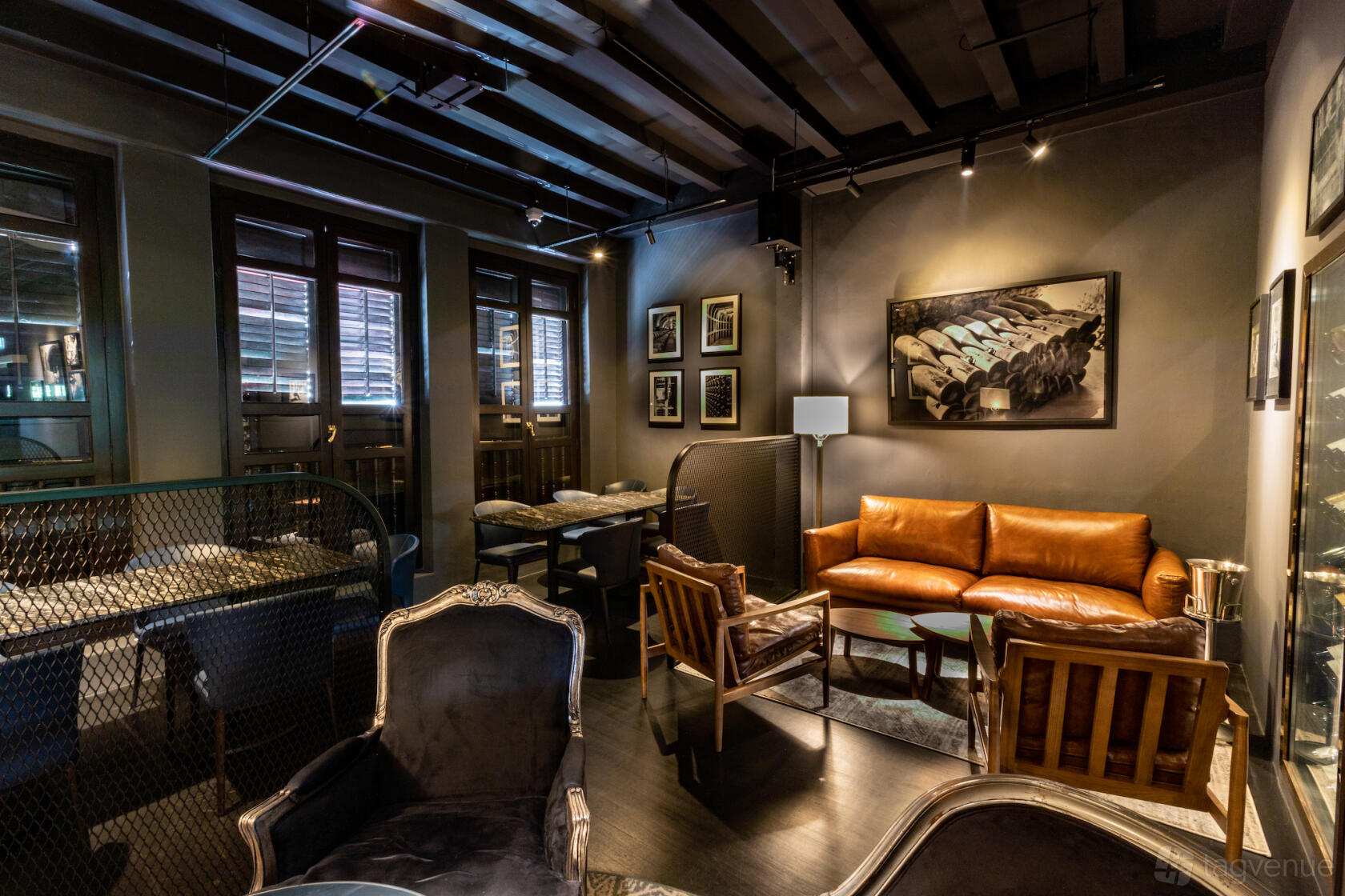 A restaurant lounge with leather sofas, vintage armchairs, framed wall art, and exposed ceiling beams at Boeuf The Cellar.