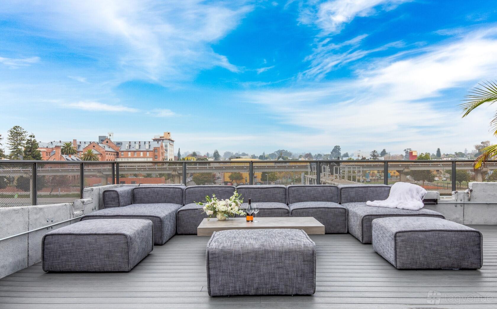 A rooftop coworking space with gray sectional sofas, a large coffee table, and city views at Artthaus Studios.