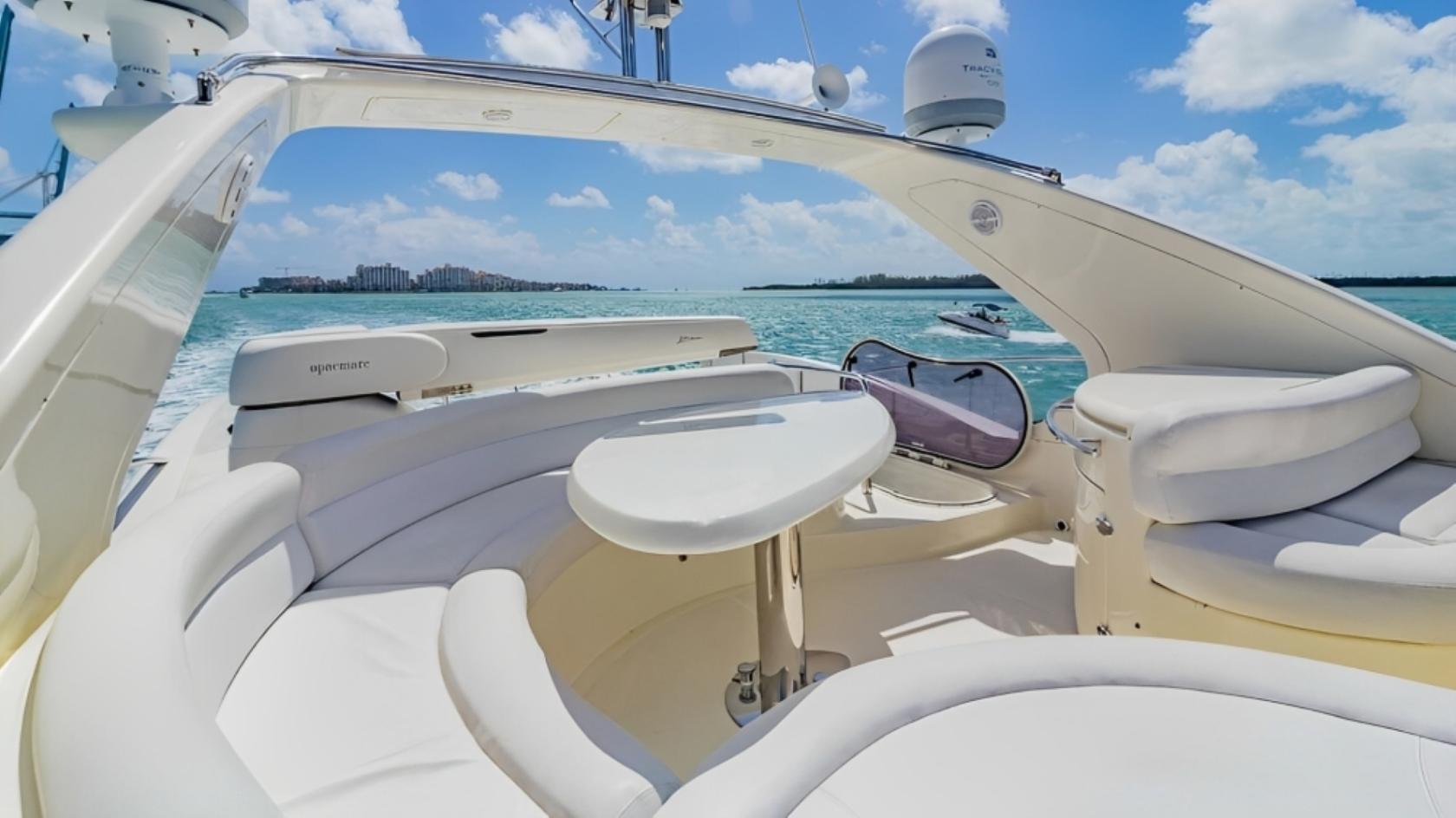 A boat deck with curved white seating, a round table, and open views of the water at Terrific Boat Charters