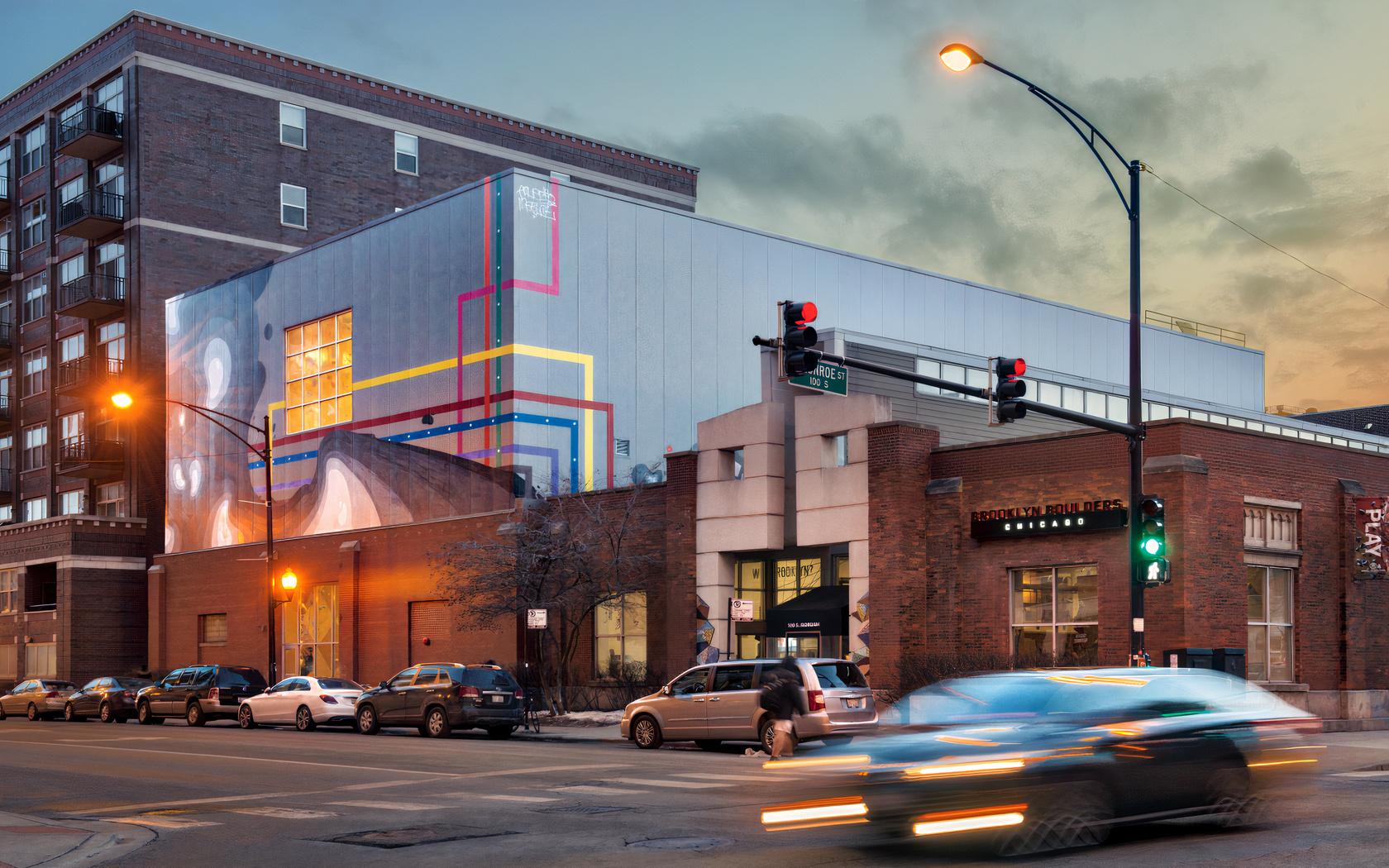 A sports hall with a modern exterior featuring colorful geometric mural panels at Brooklyn Boulders West Loop.