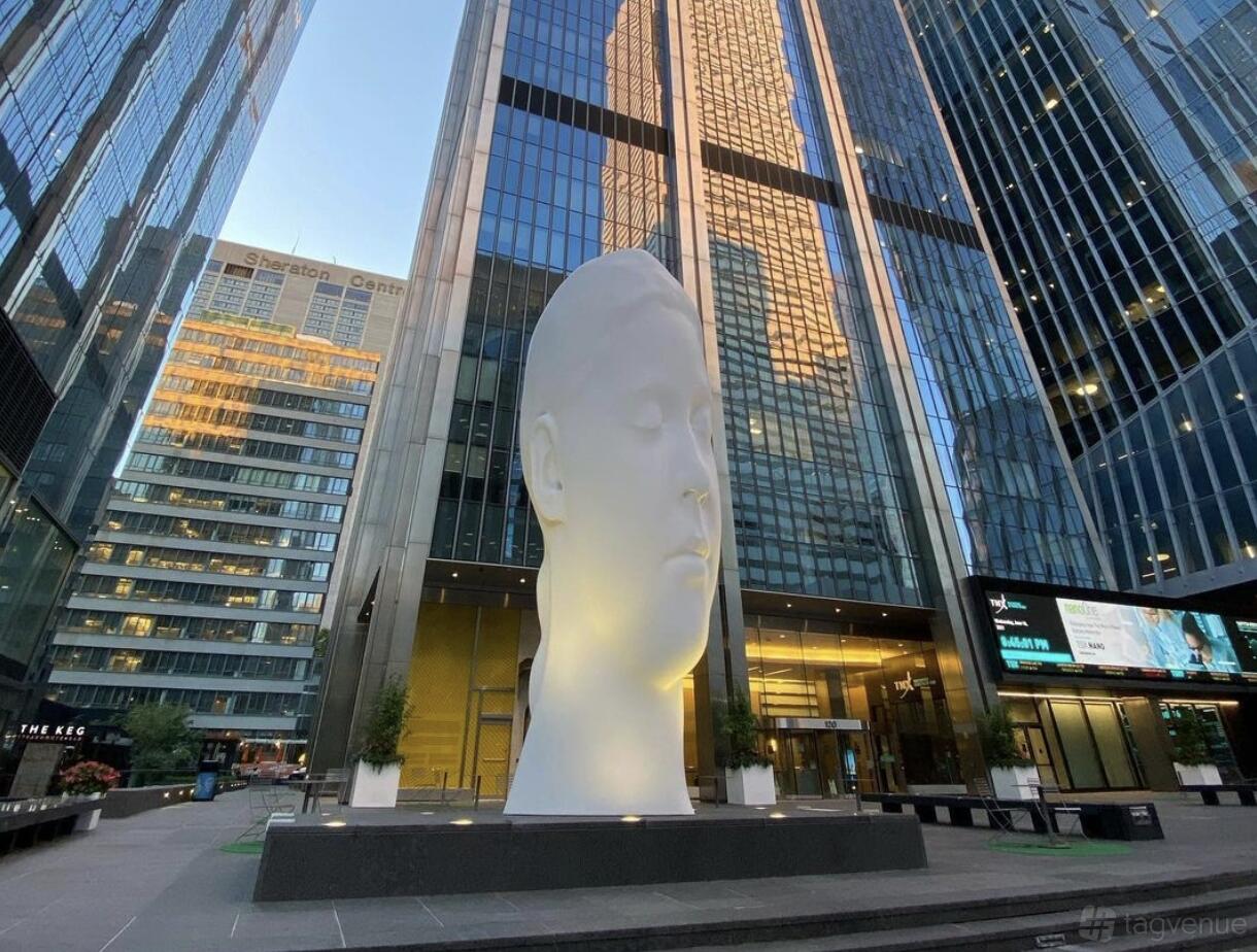 An office building courtyard with a large white sculpted head and surrounding skyscrapers at The Professional Centre.