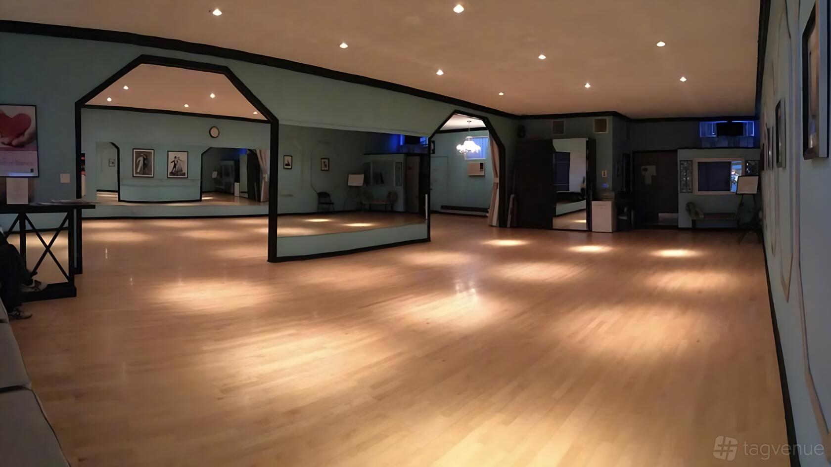 A dance studio with polished wooden floors, large wall mirrors, and framed photos at By Your Side Dance Studio Culver City.