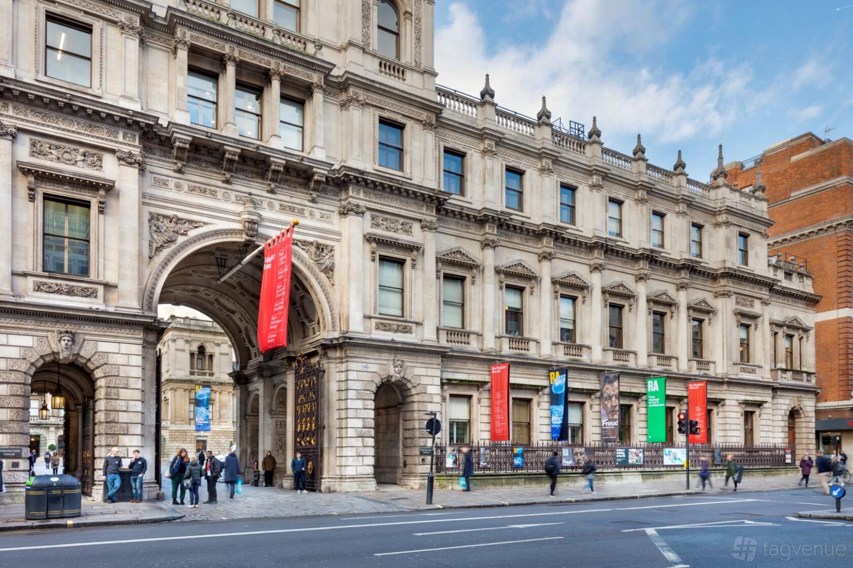 A historic building with ornate stonework, arched entrance, and colorful banners at The Geological Society.