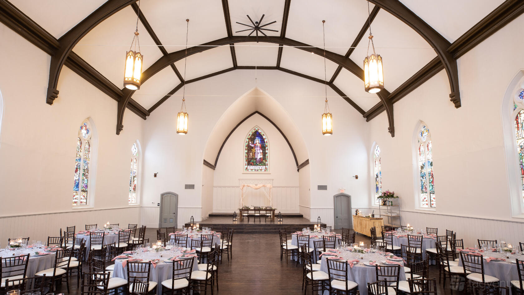 An event venue with arched ceilings, stained glass windows, and round banquet tables at Millbrook Cathedral.