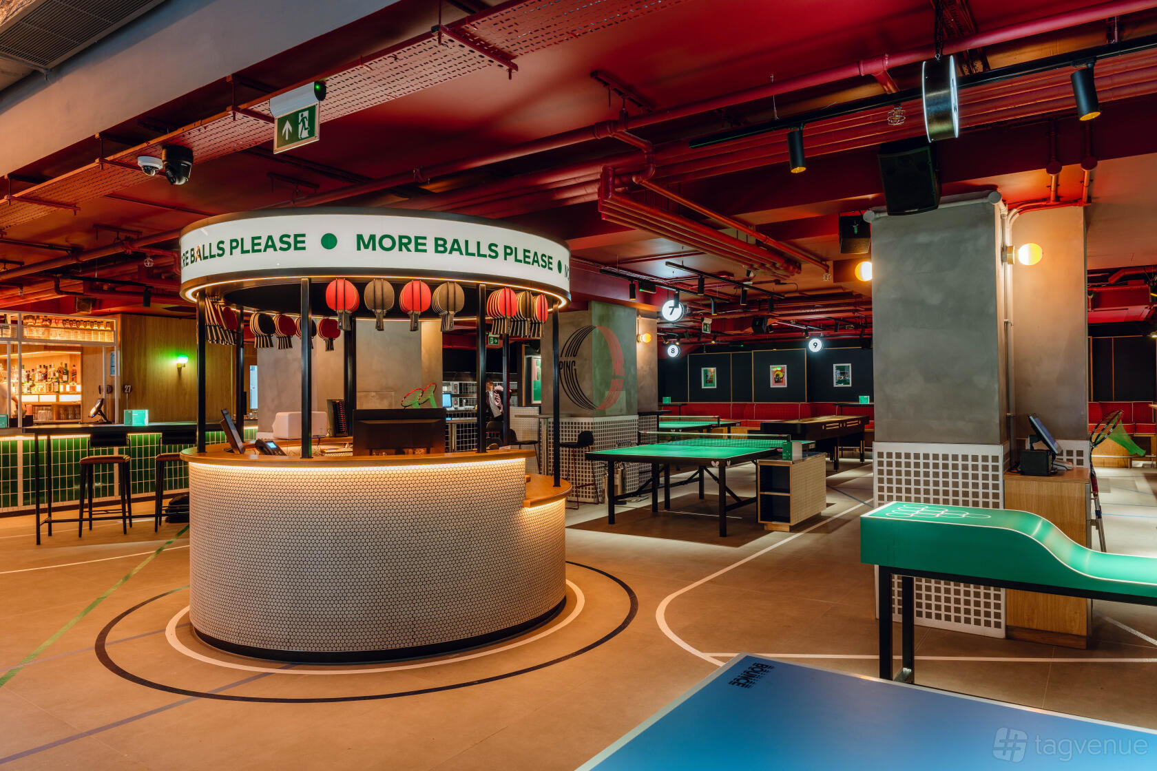 An event venue in a bar with ping pong tables, a round service counter, and neon lighting at Bounce Battersea.
