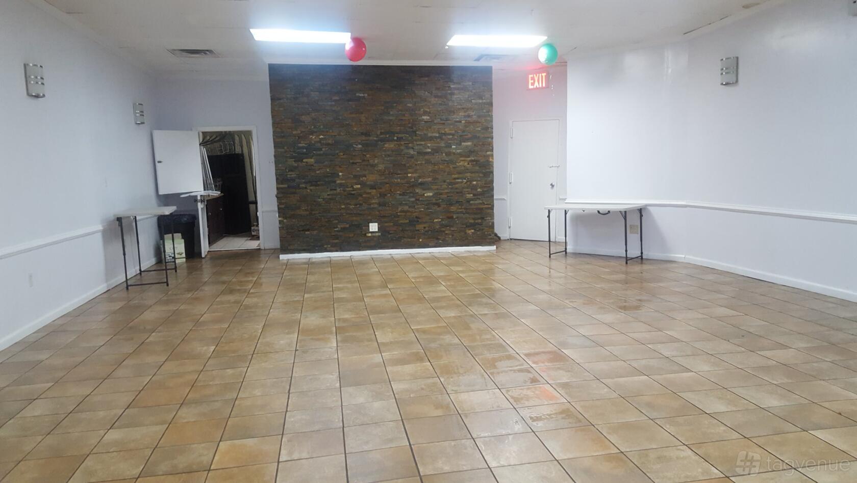 An event venue with tiled floors, a stacked stone accent wall, and folding tables at Strawberry Events.