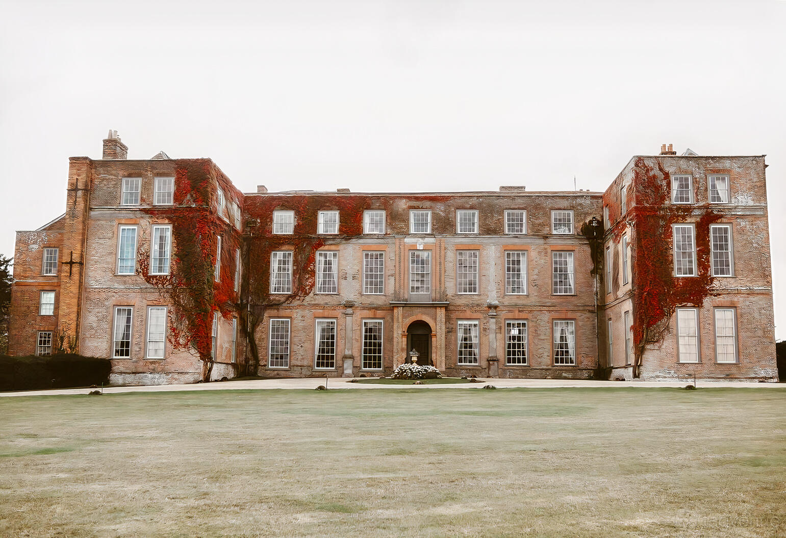 A historic country house with ivy-covered brick walls and tall sash windows at Glemham Hall.
