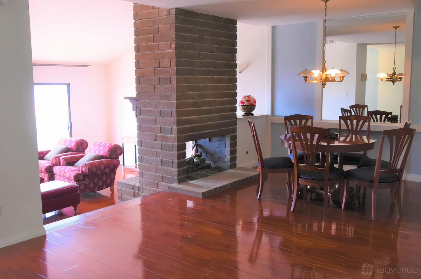 A house with polished wood floors, a brick fireplace, and a dining area with a chandelier at Ocean View Townhouse.
