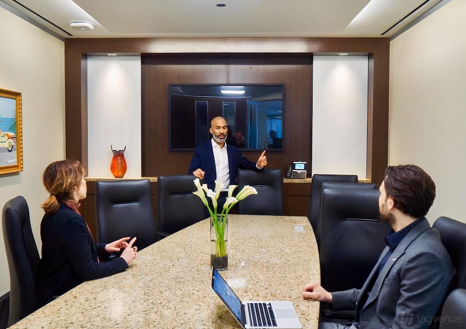 A boardroom with a marble conference table, high-back chairs, and a wall-mounted screen at Servcorp - 1330 Avenue of the Americas.