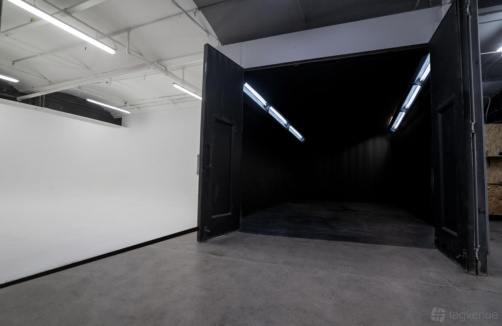 A photo studio with an all-black blackout room next to a white cyclorama wall at Submerged Spaces.