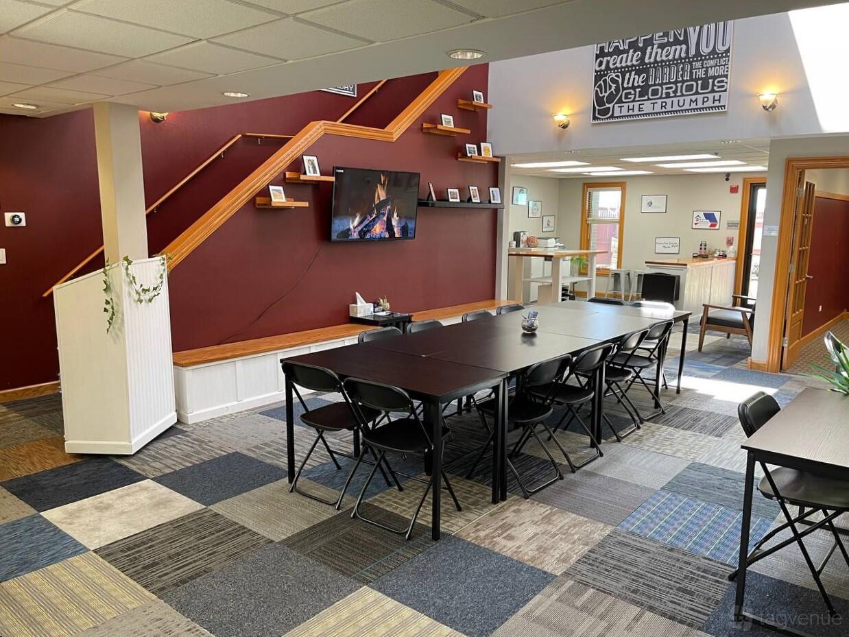 An event space with modular tables, folding chairs, a wall-mounted TV, and patterned carpet at 7030 Centennial Center.