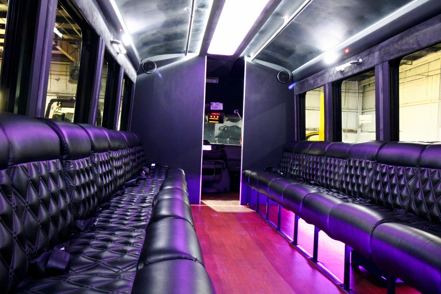 A party bus interior with black quilted leather seating, purple LED lighting, and wood flooring at GOGO Party Bus.