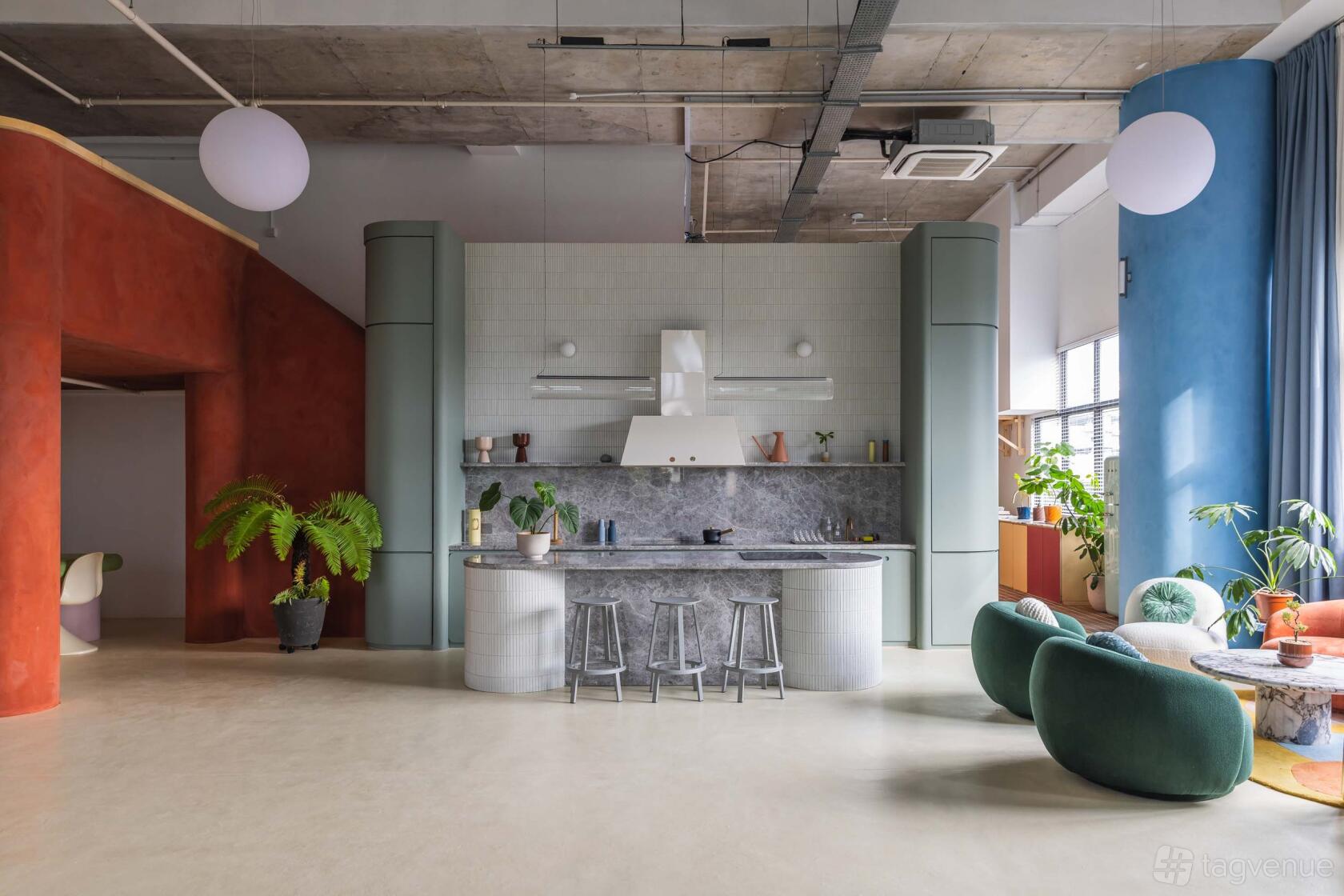 A photo studio with a kitchen island, textured walls in earth tones, and mid-century furniture at Chun Tsubaki.