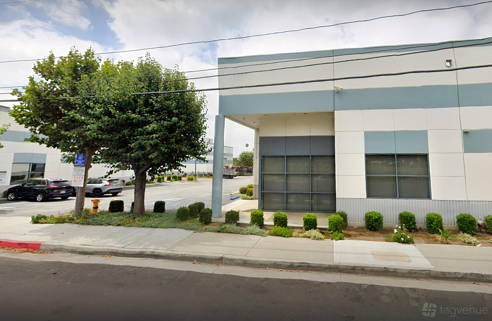 A film and photo studio with a modern facade, large windows, and landscaped bushes at Stay Lucky Studios.