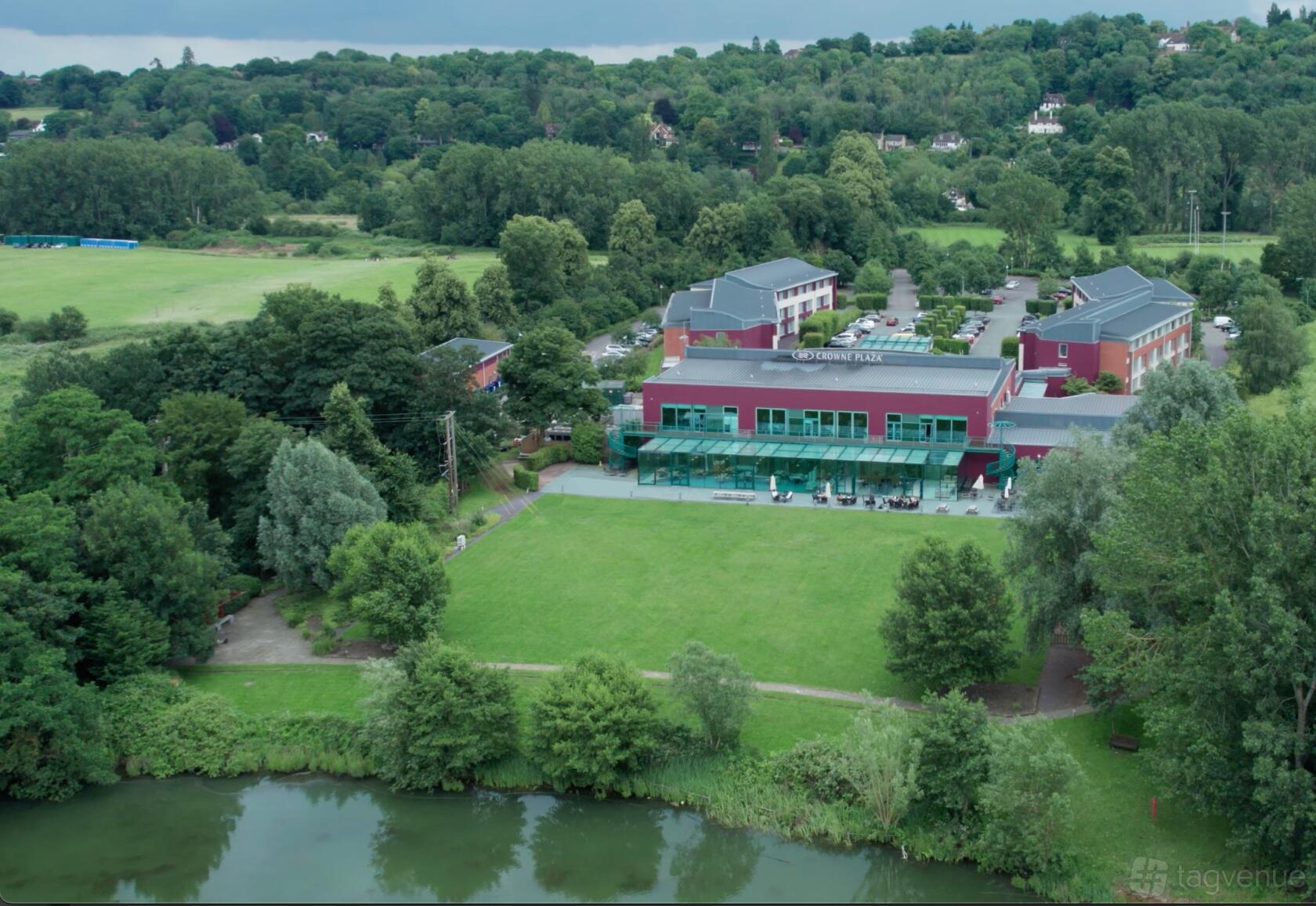 A hotel with a large glass-walled terrace, spacious lawn, and riverside location at Crowne Plaza Marlow.