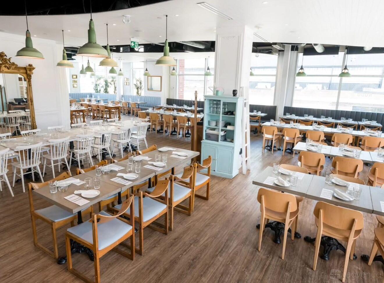An event space in a restaurant with wooden floors, pendant lighting, and mixed seating at Nodo Liberty.