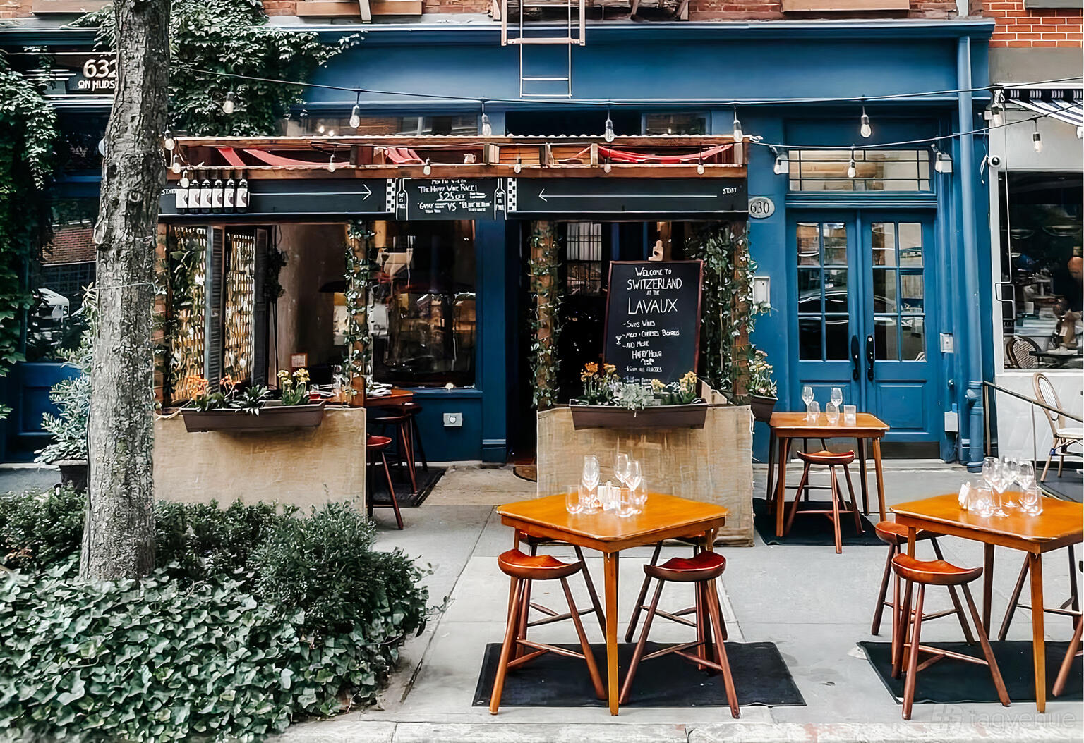 A restaurant with outdoor tables, wooden chairs, and string lights at The Lavaux Wine Bar.