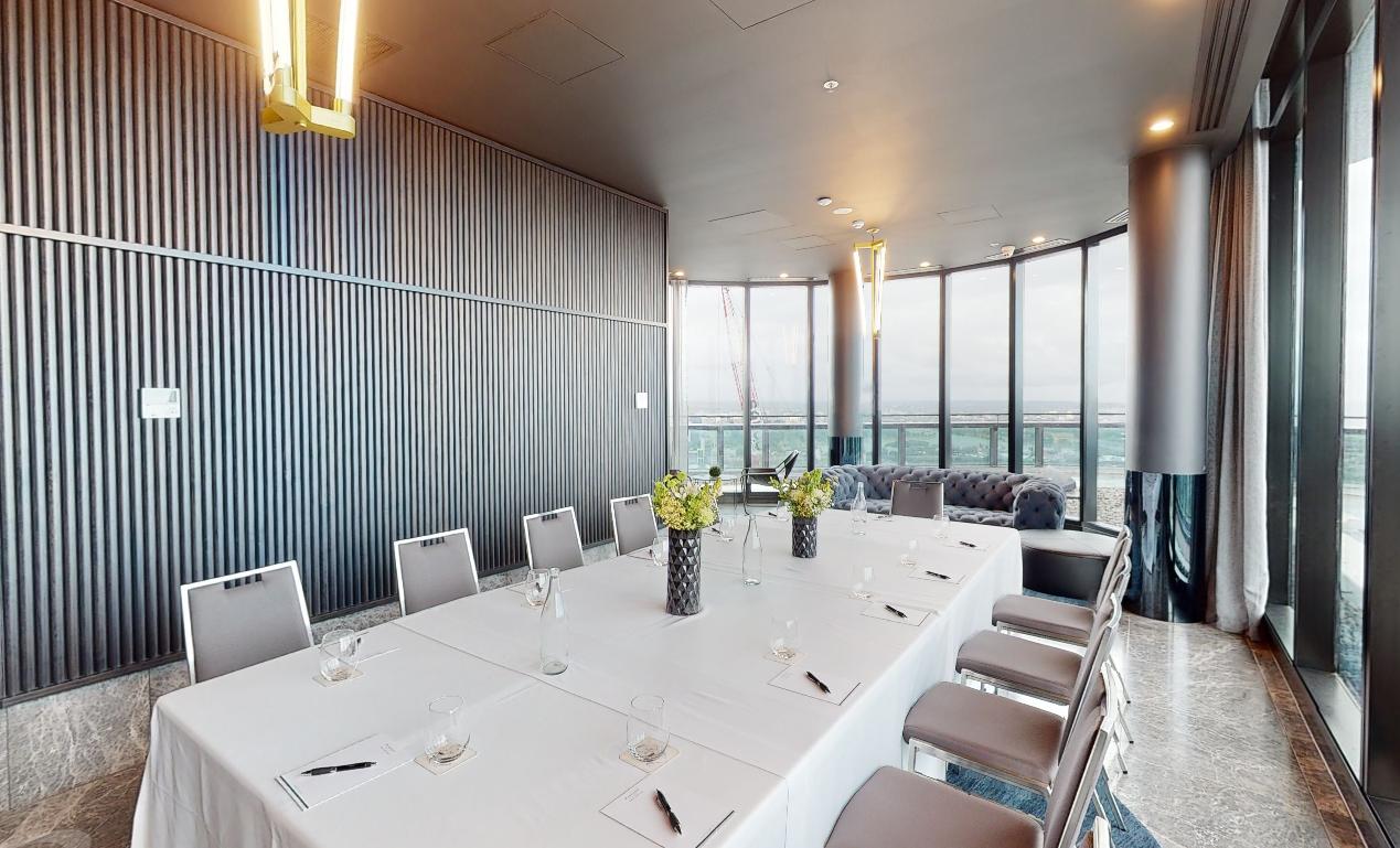 A function room with floor-to-ceiling windows, a long conference table, and floral centerpieces at Shadow Play by Peppers.