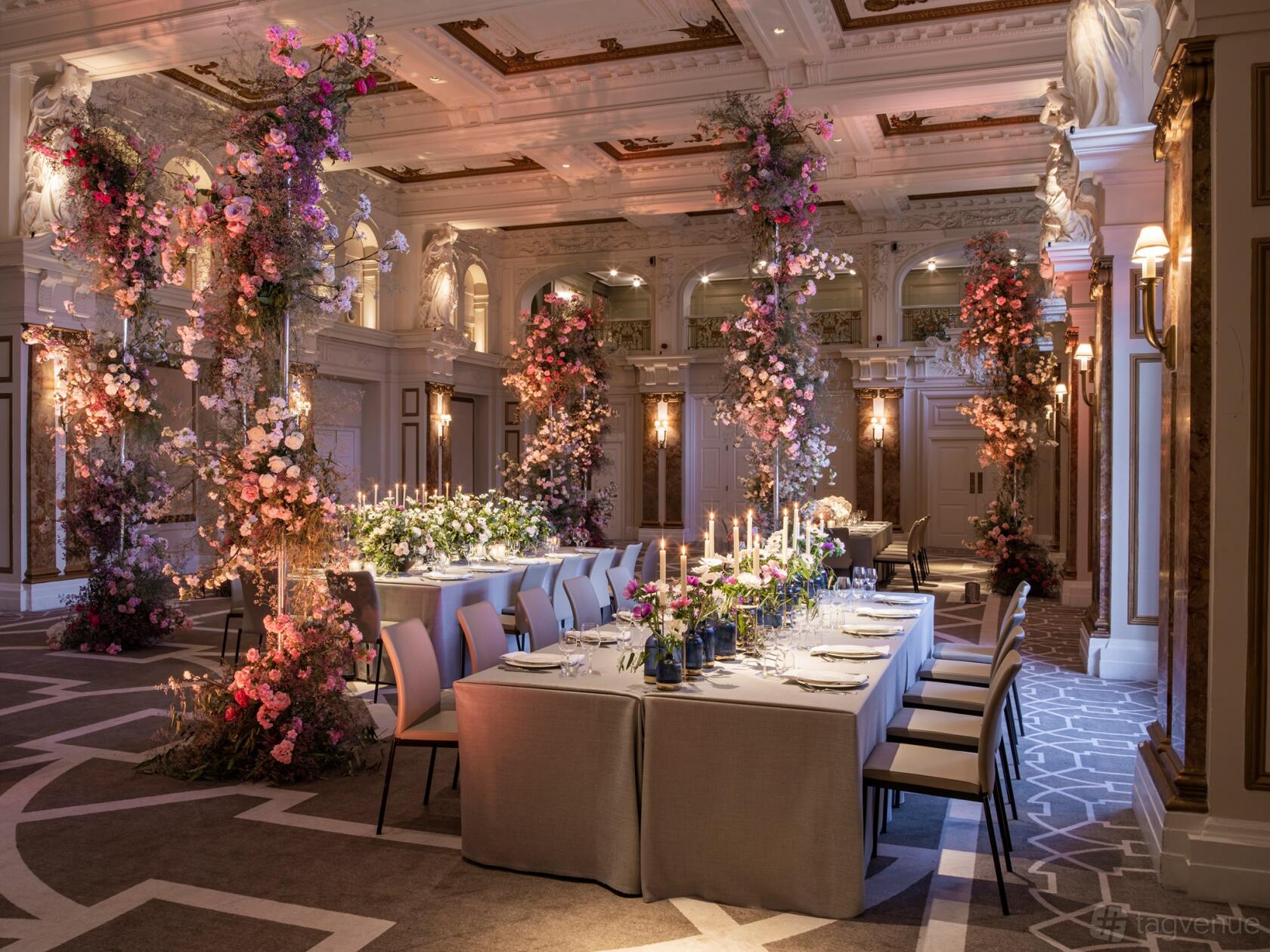 A hotel ballroom with ornate ceilings, floral arrangements, and long tables with candles at Kimpton Fitzroy London.