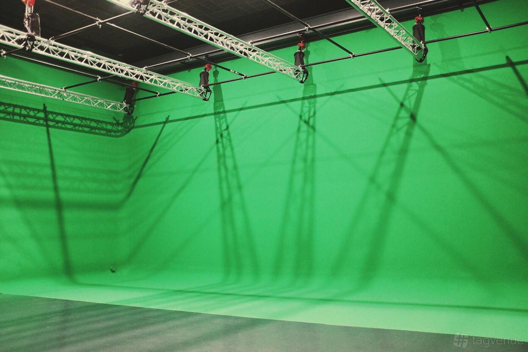 A photo studio with a large green cyclorama wall and overhead lighting grid at HitMaker Studio.