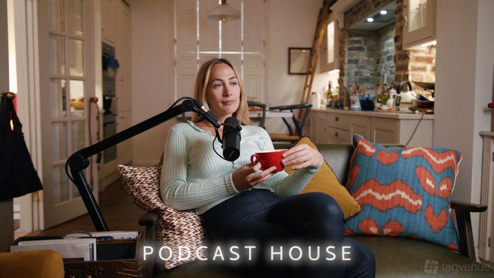A podcast studio in a house with a microphone arm, cozy seating, and patterned pillows at Wilmington Square GII Period Property.