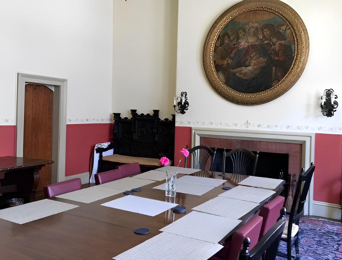 A church meeting room with a long wooden table, pink chairs, and a large religious painting at Emmanuel Episcopal Church Of Boston.