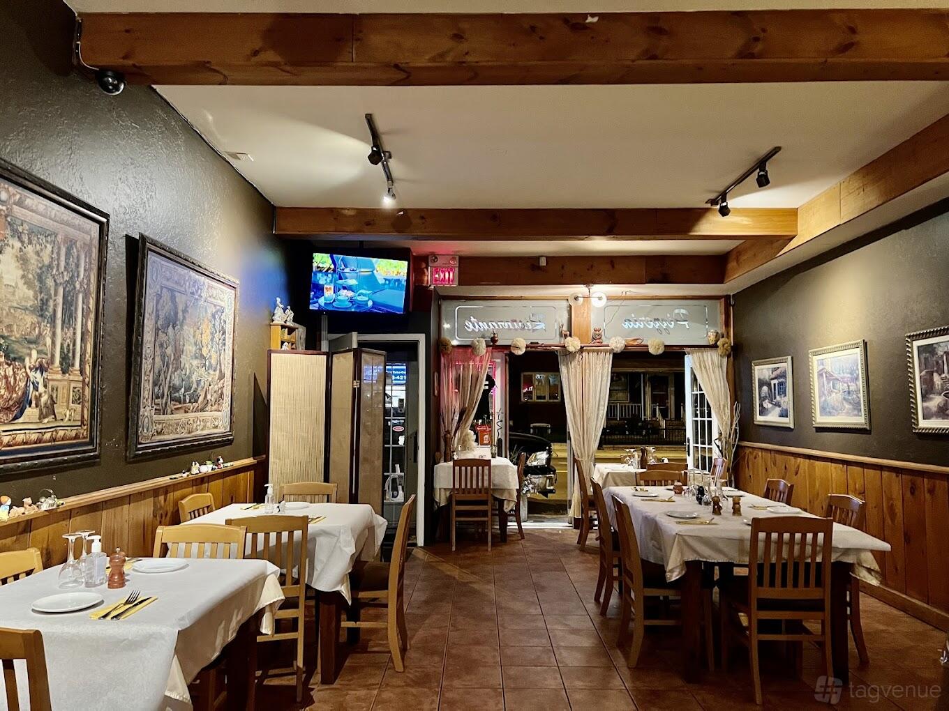 A restaurant dining room with wood-paneled walls, framed artwork, and tables covered with white linens at La Grotta Ristorante Pizzeria.