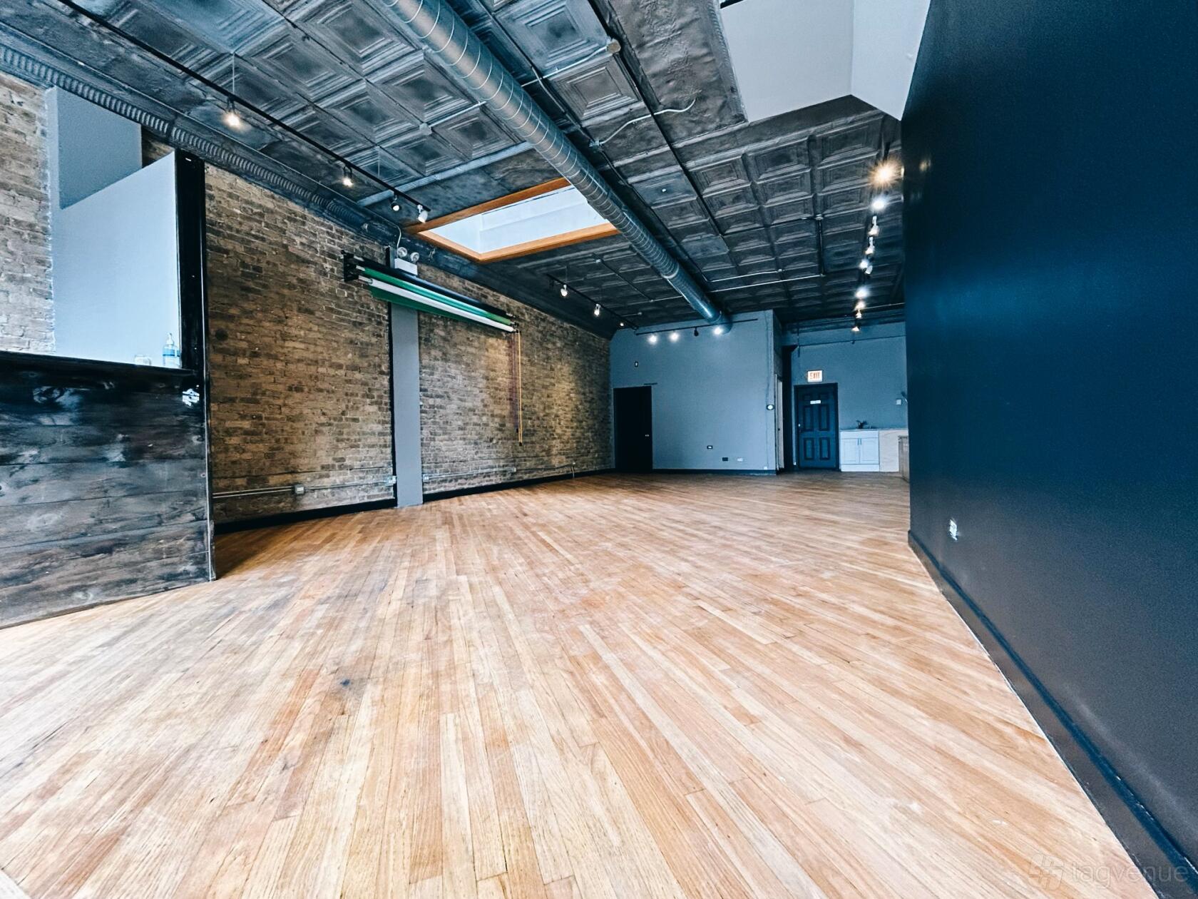 A blank canvas event venue with exposed brick walls, hardwood floors, and a skylight at Studio 424.