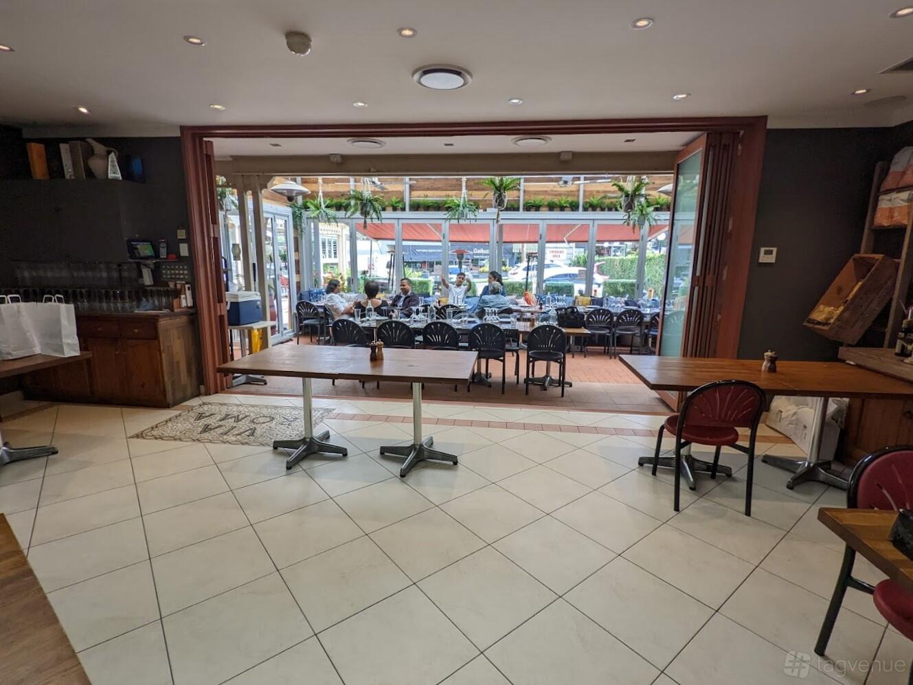 A restaurant with tiled floors, wooden tables, and a covered patio with outdoor seating at Il Posto.