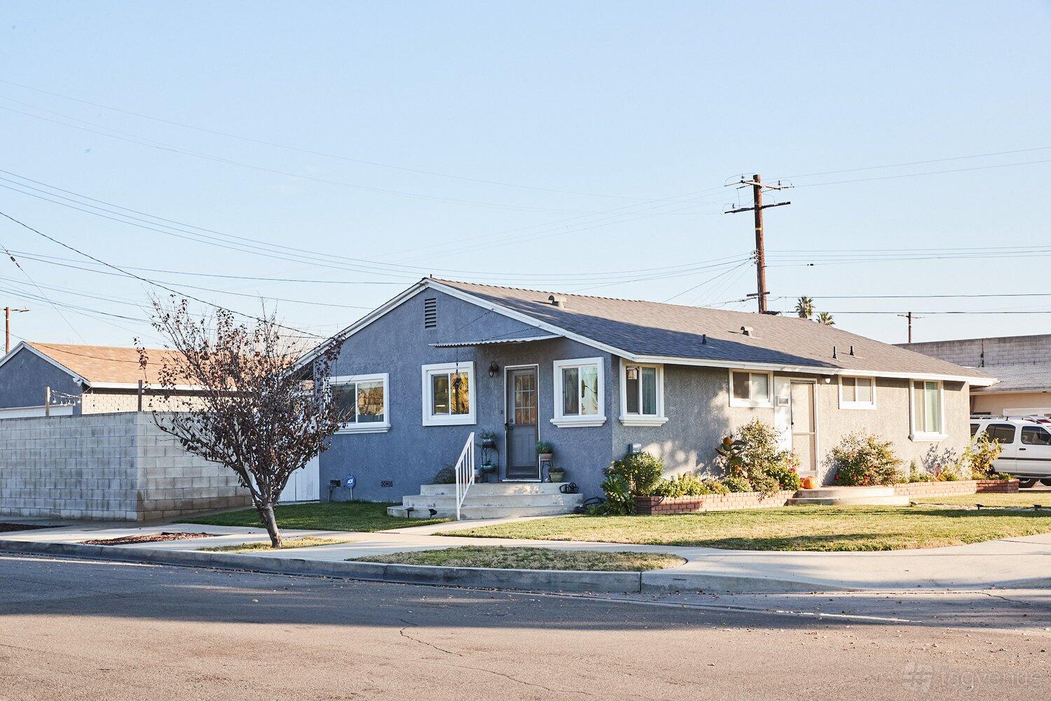 A single-story apartment with gray siding, a small front porch, and landscaped yard at Lombard.