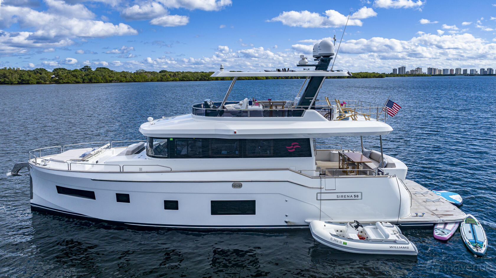 A yacht with an upper sundeck, shaded seating area, and docked tender at Lots Of Yachts/Lots Of Spots South Florida.