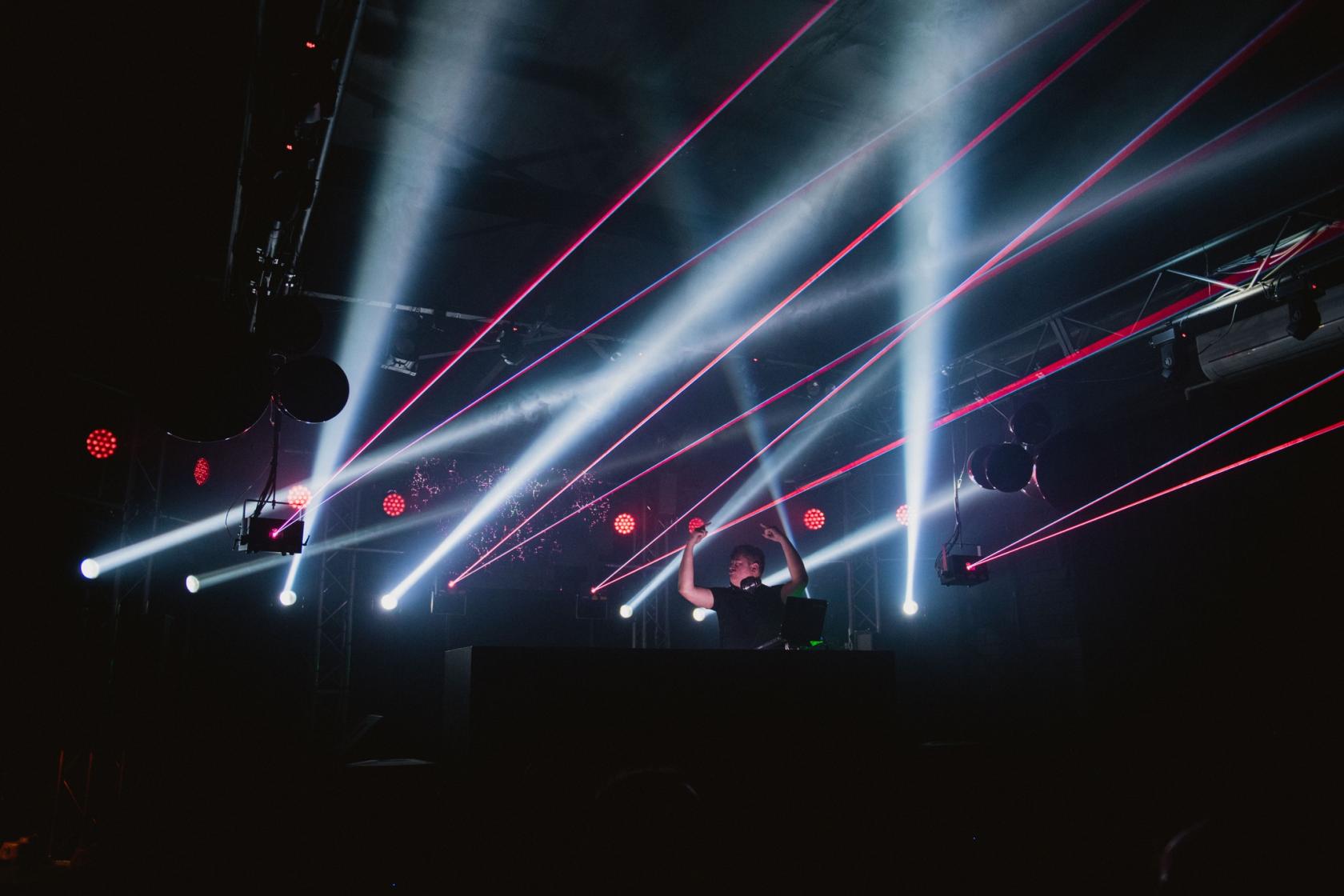 A live music venue with dramatic stage lighting, lasers, and a DJ booth at RUBIX Warehouse.