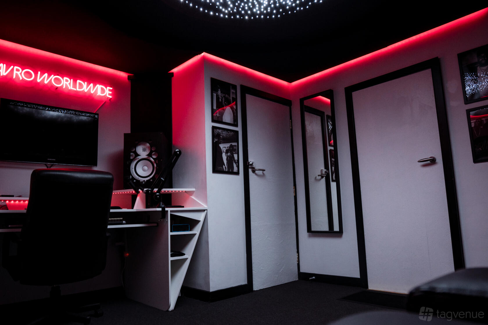 A recording room with neon lighting, sound monitors, and framed wall art at Mavro Worldwide Studios.