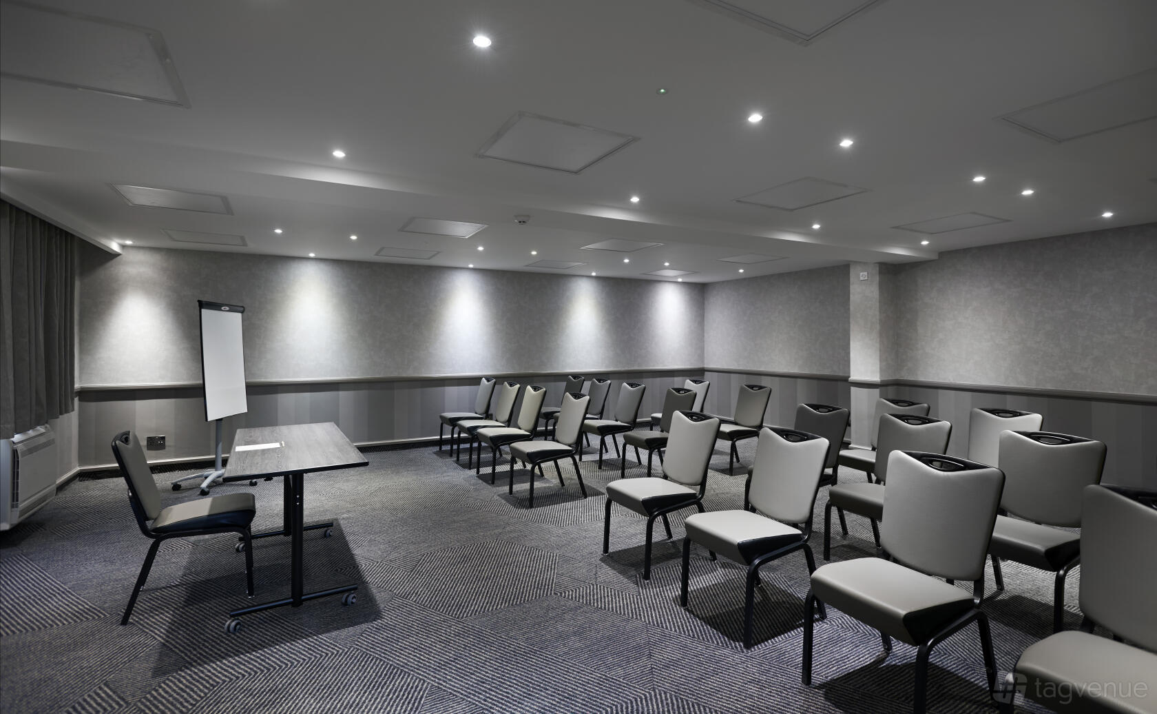 A meeting room with rows of cushioned chairs, a presenter’s table, and a flip chart at DoubleTree by Hilton Bristol North.