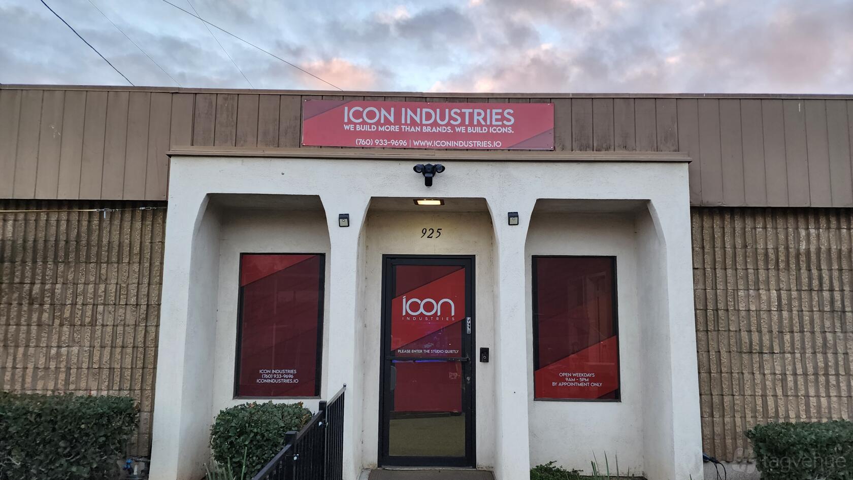 A film and photo studio with a white facade, red signage, and large front windows at Icon Industries Inc. Studio.