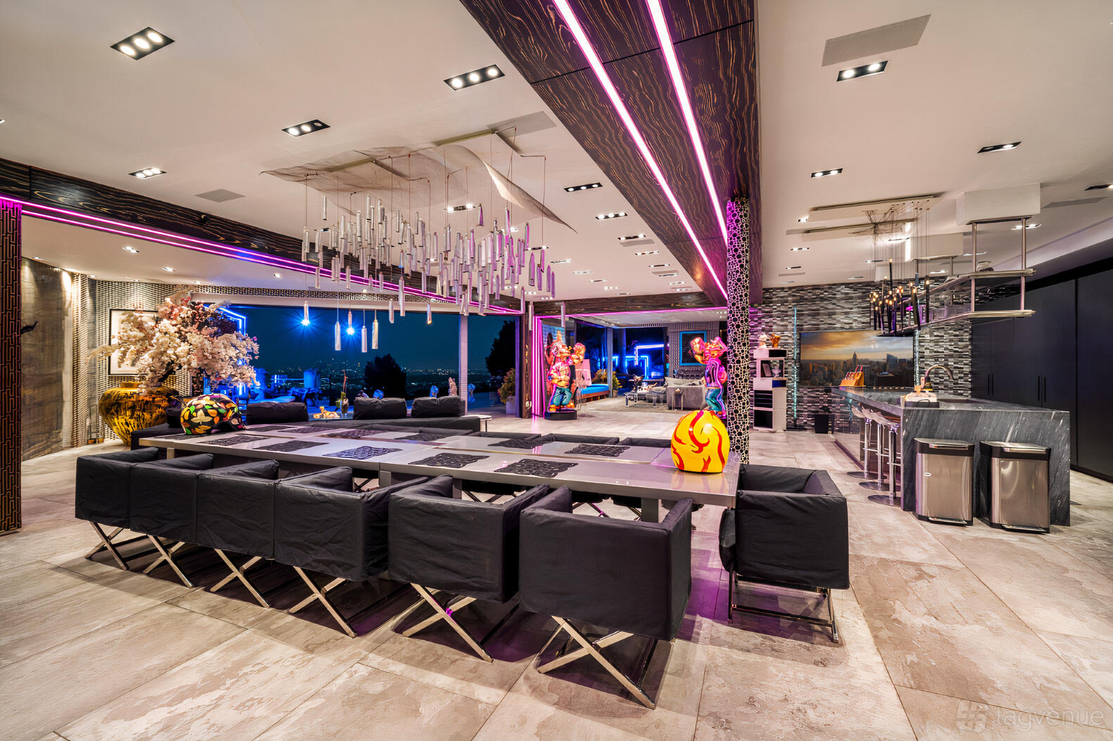 An event venue with long dining tables, modern lighting fixtures, and floor-to-ceiling windows at The Sunsetview Villa.
