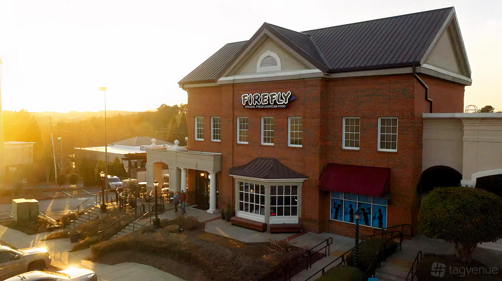 A brick pub with large windows and white columns at the entrance at Firefly Grill & Bar.