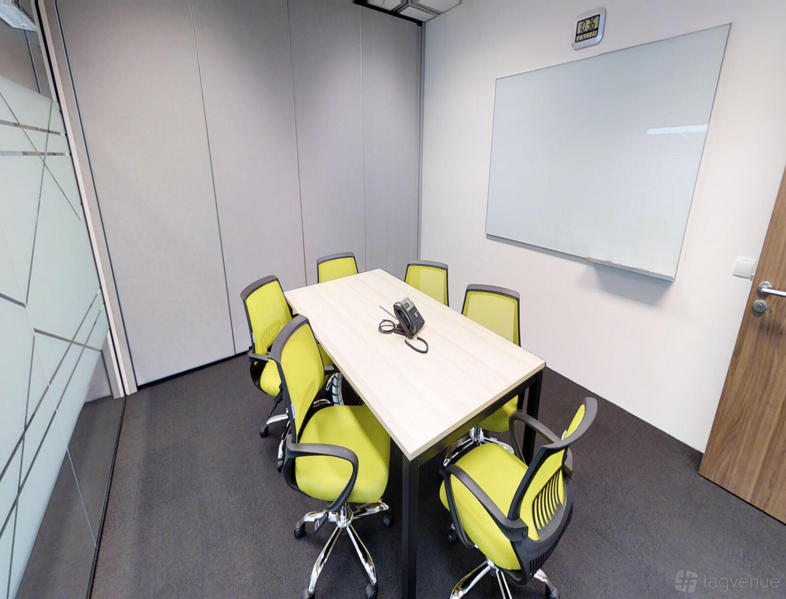 A meeting room with a rectangular table, six lime green chairs, and a wall-mounted whiteboard at Suntec City.