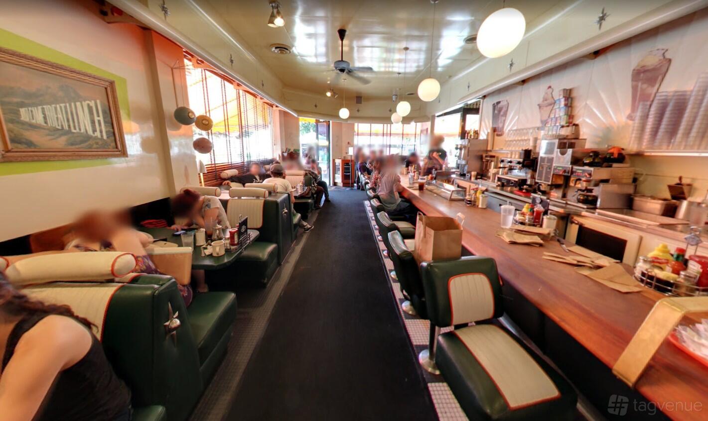 A retro diner restaurant with booth seating, a long counter with stools, and globe pendant lighting at FRED62.