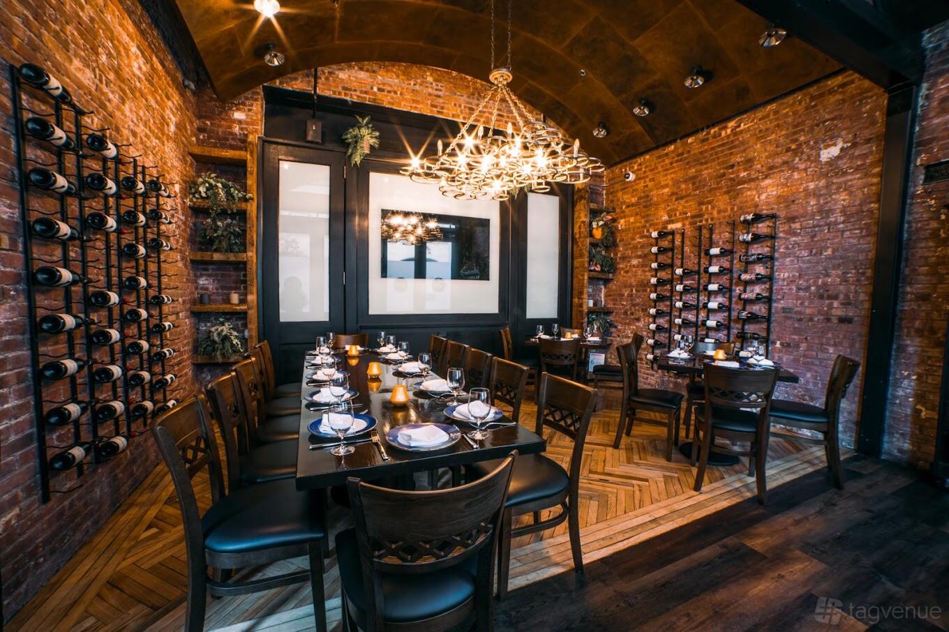 A dining room with exposed brick walls, wine racks, and a long table set for guests at Paisley.