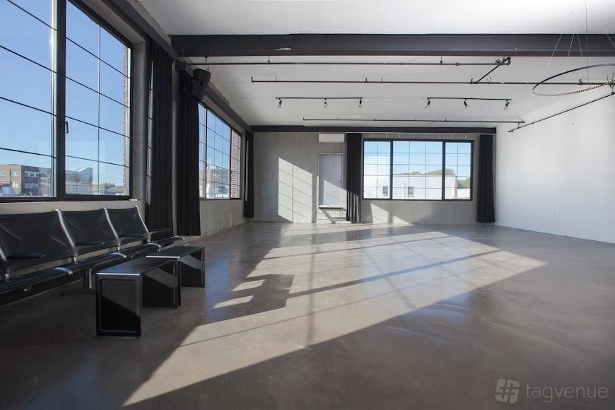 A photo studio with large industrial windows, polished concrete floors, and black seating at Vandervoort Studio.