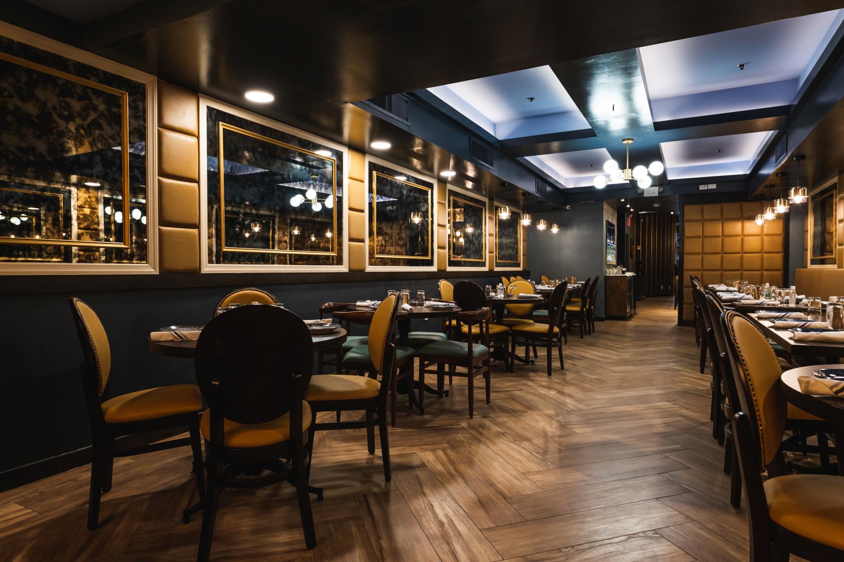A restaurant dining room with gold-upholstered chairs, wooden flooring, and mirrored wall panels at Akdeniz Mediterranean Cuisine.