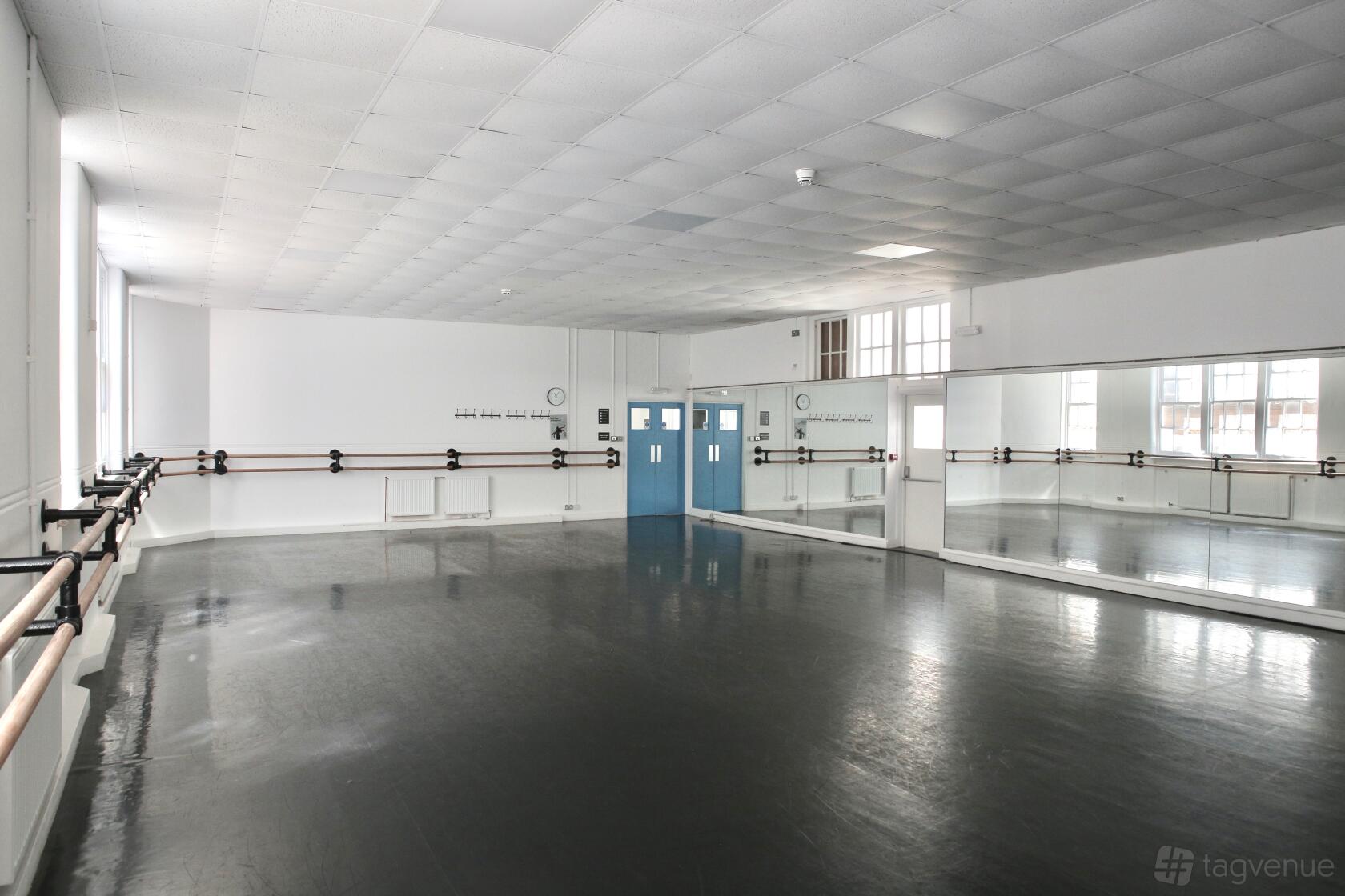 A dance studio with floor-to-ceiling mirrors, ballet barres, and natural light at City Academy at 10 Herbal Hill.
