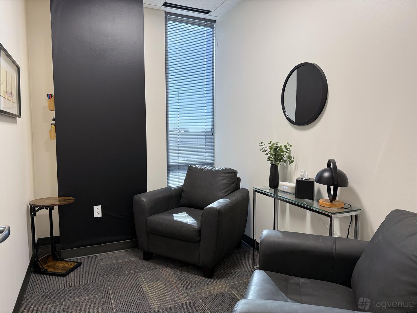A meeting room with black armchairs, a glass console table, and a large window at Executive Workspace Plaza at Legacy.